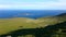 Top view, aerial panorama of the endless green slope descending to the blue ocean and islands. Clear summer sky. Norway