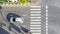 Top view aerial photo of a driving motorcycle and bus on asphalt track and pedestrian crosswalk in traffic road with light and