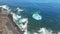 Top view aerial of a volcanic coastline with waves breaking on a rocky beach