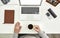 Top view of aged male employee senior intern holding a cup of coffee while sitting at desk in modern office, Notebook