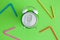 Top view of alarm-clock soda can and multicolored drinking straws abstract on green