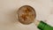 Top view alcoholic drink being poured in glass with ice cubes on wooden table, rum or whiskey drink