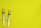 Top view of ampoules with coronavirus vaccine and syringes on yellow background. Closeup 3d concept on medical theme. 3d