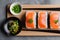 Top view of appetizing sliced salmon sashimi served on plate with sushi rolls and greenery placed