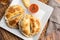 Top view of an Argentinian homemade empanadas on square white plate, red sauce and lemon slices