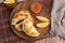 Top view of the Argentinian homemade empanadas on wooden plate with red sauce and lemon slices