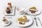 Top view of arrangement of pieces of various cakes on plates, cups of coffee and cupcakes