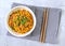 Top view of asian vegetarian chili noodles with bamboo chopsticks