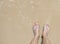 Top view of Asian woman feet wearing a blue slipper on ocean sandy beach