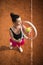 Top view of attractive young woman tennis player serving on a clay tennis court.