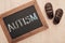 Top view of autism lettering written on chalkboard near children brown sneakers on wooden surface.