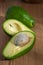 Top view of avocados, one cut, with selective focus, on wooden board and natural light