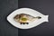 a top view of baked filled dorado served on a white herring-dish