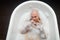 Top view of a bald man with a red beard splashing in the foam bath. Humorous photo. A parody of glamorous girls.