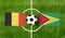 Top view ball with Belgium vs. Guyana flags match on green football field