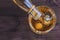 Top of view of barman pouring whiskey in the glass with ice cubes on wood table background, focus on ice cubes