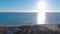 Top view of beach with blue sea and sun on horizon. Art. People on beach relax enjoying blue horizon of touching sea and