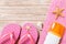 Top view of Beach flat lay accessories. sunscreen bottle with seashells, starfish, towel and flip-flop on wooden board background