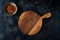 Top view of a beautiful cutting board, a bowl of red spices, and a decorative cloth on a dark blue background