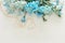 Top view of beautiful and delicate blue flowers arrangement next to pearls necklace