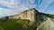 Top view of beautiful white rock with green grass on background of blue sky. Shot. Panorama of white cliff with green