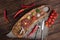 Top view on Beef Tartar with a raw egg yolk, rye bread and chilis on a wooden board and rough cloth with spoon and fork. Shot made