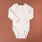 Top view beige milk baby bodysuit on brown background, mock up, copy space