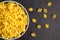 Top view of black background with italian raw conchiglie paste shells in bowl with copy space