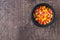 Top view of a black ceramic cauldron of holiday candy corn on a rustic wood background