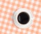 Top view of black coffee cup on checked tablecloth