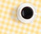Top view of black coffee cup on checked tablecloth