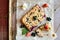 Top view of black currant, strawberry and cottage crumble cake on baking paper and rustic background