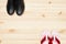 Top view of black leather shoes and beach slippers on wooden background