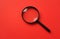 Top view  Black round magnifying glass on red background. used for searching or expanding books.