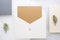 Top view of blank gold card in white envelop with pine leaf on t