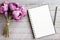 Top view of blank notebook, clock, pen and green plant on wooden pallet background