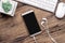 Top view of blank smartphone, earphones, keyboard and mouse on grunge wooden desktop. Flat lay mock up image