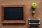 Top view of blank wooden chalk board, apple, dumbbells and measuring tape,