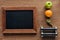 Top view of blank wooden chalk board, fruits, dumbbells and measuring tape,