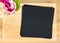 Top view of Blank wooden plate with black paper and flower pot on table