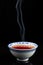 Top view of blue china tea cup, steaming, black background, vertical,