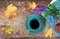 Top view of a blue cup of coffee, book, flowers, cookies and leaves on wooden background