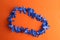 Top view of a blue plastic party necklace on an orange background