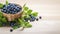 Top view blueberry and green leaves in a wooden bowl on wooden table