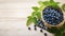 Top view blueberry and green leaves in a wooden bowl on wooden table