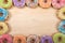 Top view border of colorful candy sprinkled donuts on wood table