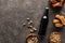 Top view of bottle of dark beer near bowls with nuts and chicken snacks on brown surface.