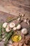 A top view of a bottle of olive oil next to garlic, mushrooms and rosemary. Vegetable set on a wooden table background.