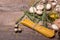 A top view of a bottle of olive oil next to pasta, mushrooms and rosemary. Vegetable set on a wooden table background.