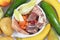 Top view of bowl with dog food consisting of raw beef and chicken meat, salmon fish, fruits and vegetables surrounded by healthy i